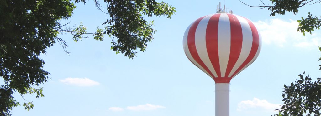 Red and white striped water tower; tree branches surround it